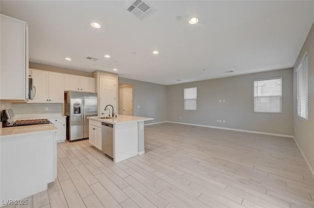 kitchen featuring visible vents, a sink, stainless steel appliances, light wood finished floors, and light countertops