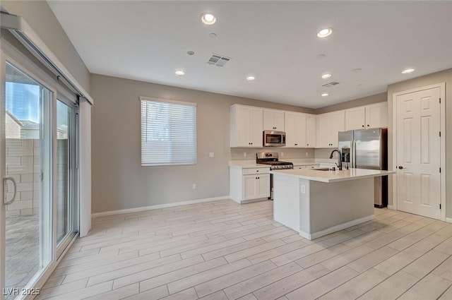 kitchen featuring visible vents, light countertops, appliances with stainless steel finishes, white cabinetry, and a sink