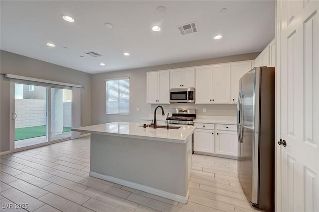 kitchen with a sink, stainless steel appliances, visible vents, and light countertops