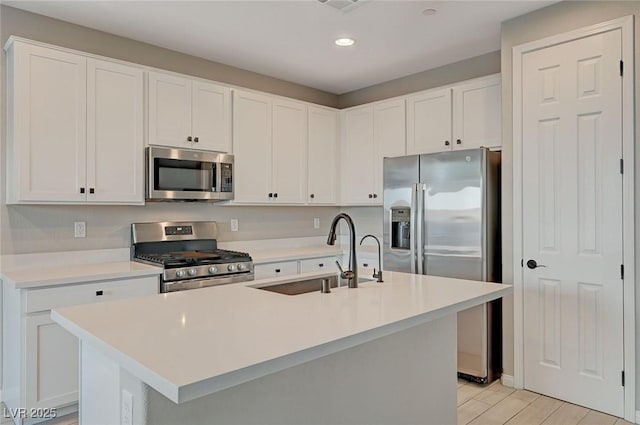 kitchen featuring a sink, appliances with stainless steel finishes, light countertops, and white cabinetry