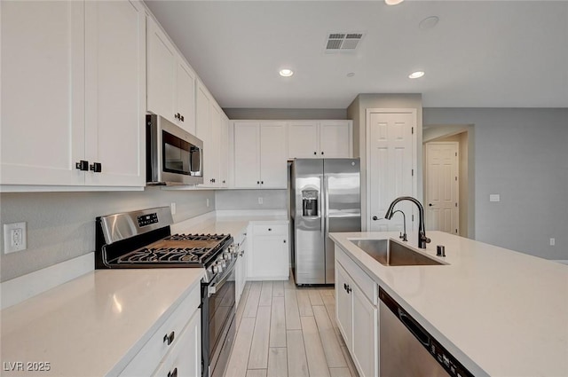 kitchen with appliances with stainless steel finishes, light countertops, light wood-style floors, and a sink