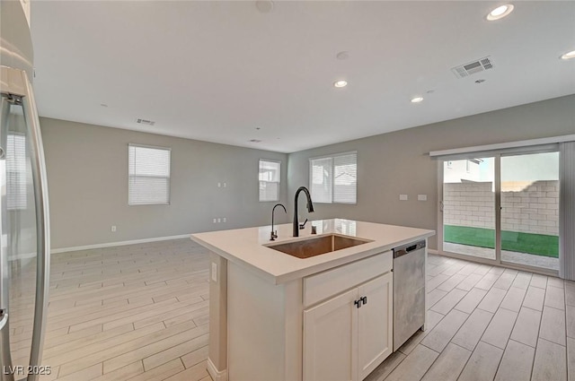 kitchen with visible vents, an island with sink, a sink, appliances with stainless steel finishes, and light countertops