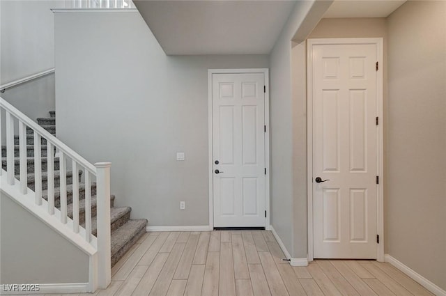 foyer featuring stairway, wood finished floors, and baseboards