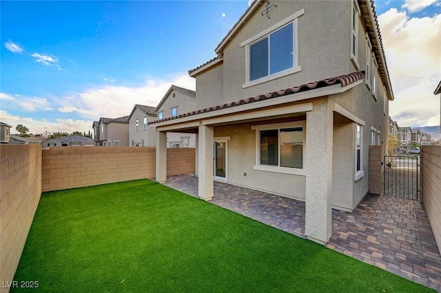 back of house with stucco siding, a patio, a fenced backyard, a yard, and a tiled roof