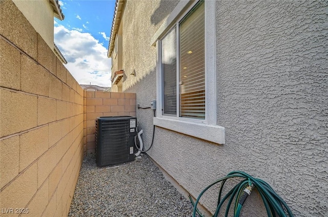 view of home's exterior featuring central air condition unit, stucco siding, and fence