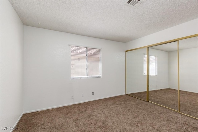 unfurnished bedroom with a closet, visible vents, carpet flooring, and a textured ceiling