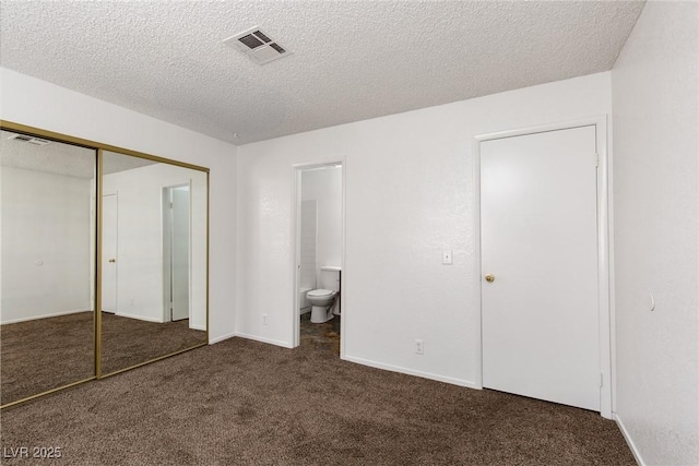 unfurnished bedroom with visible vents, a textured ceiling, a closet, connected bathroom, and dark colored carpet