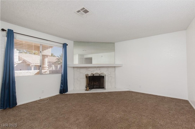 unfurnished living room featuring visible vents, baseboards, carpet floors, a fireplace, and a textured ceiling