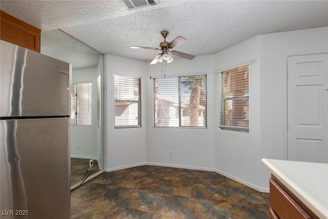 unfurnished dining area with visible vents, baseboards, a textured ceiling, and stone finish floor