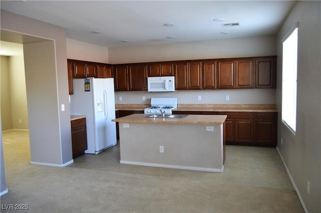 kitchen with white appliances, visible vents, light countertops, light carpet, and a center island