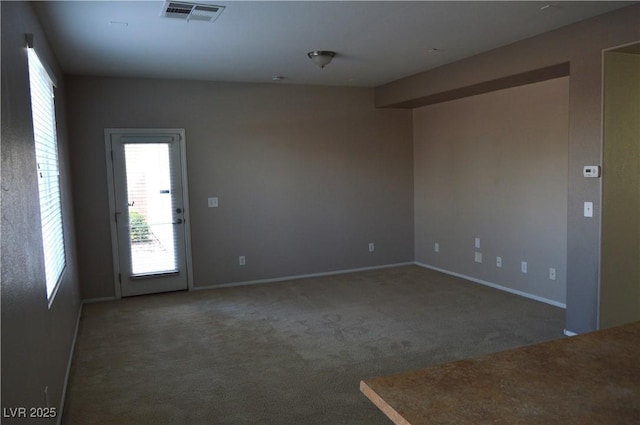 carpeted spare room featuring visible vents and baseboards