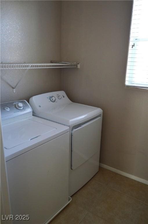 clothes washing area featuring laundry area, baseboards, tile patterned floors, and washing machine and clothes dryer