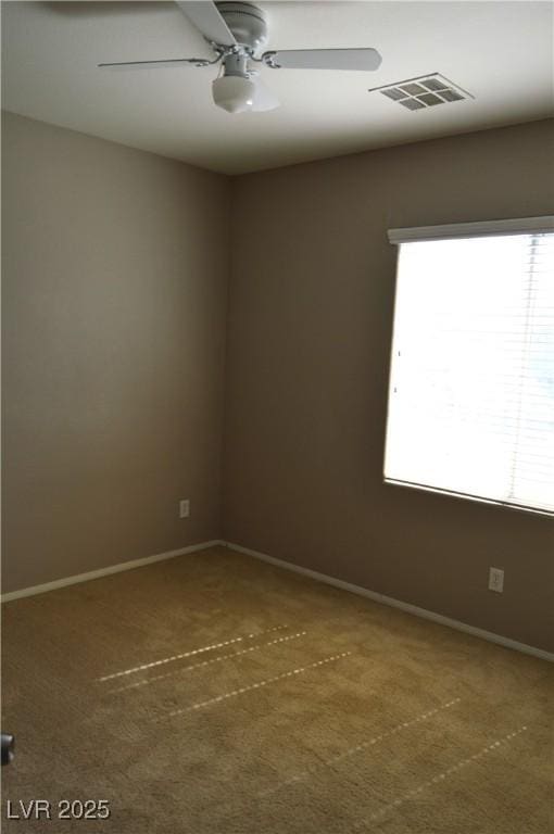 carpeted empty room featuring a ceiling fan, visible vents, and baseboards