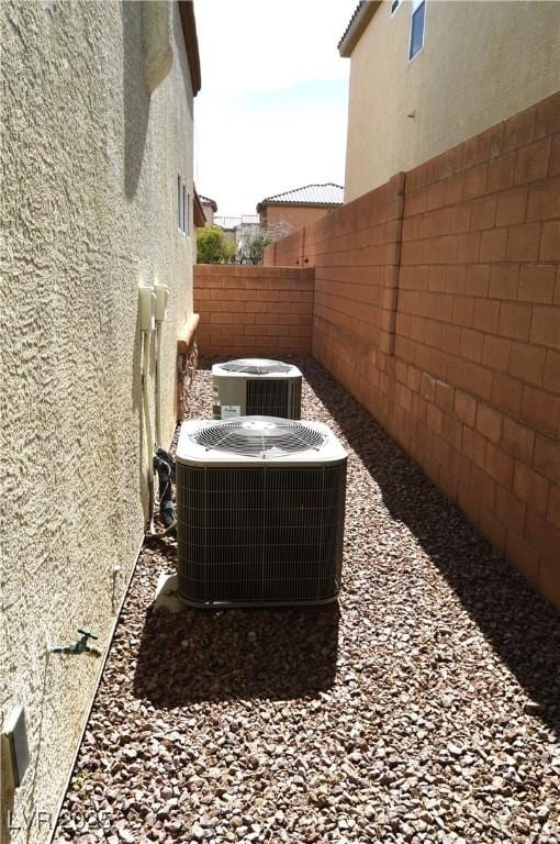 exterior details featuring stucco siding, central AC unit, and a fenced backyard