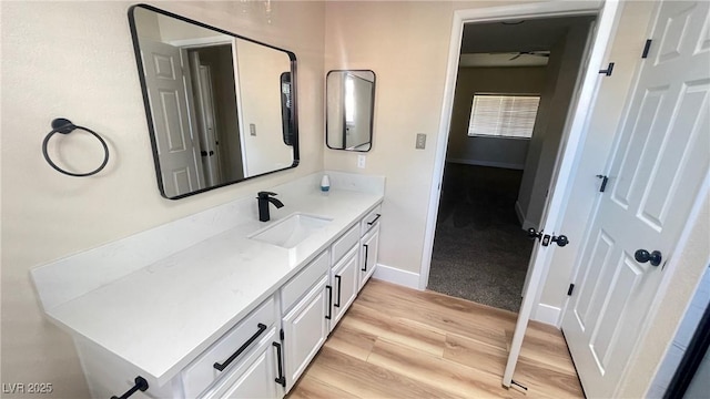 bathroom featuring vanity, baseboards, and wood finished floors