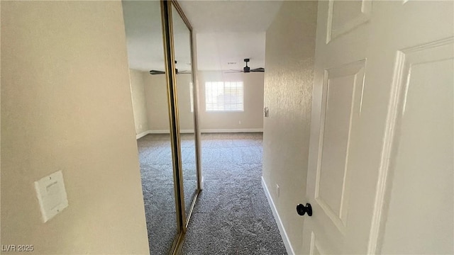 corridor featuring baseboards and carpet flooring