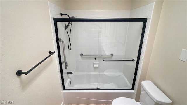 bathroom with toilet and combined bath / shower with glass door