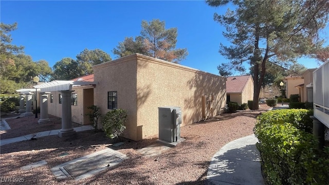 view of property exterior featuring stucco siding and a pergola