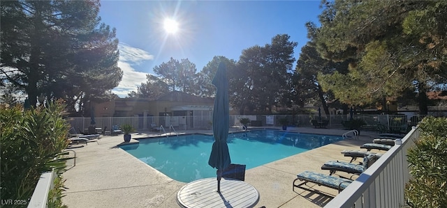 pool with a patio area and fence