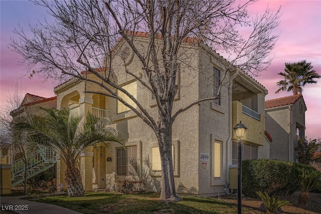 view of front of property with stucco siding, stairs, and a tile roof