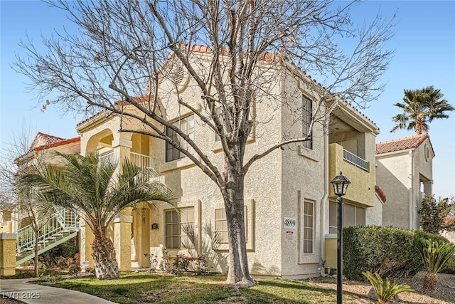 view of front facade with stairway, stucco siding, and a tiled roof