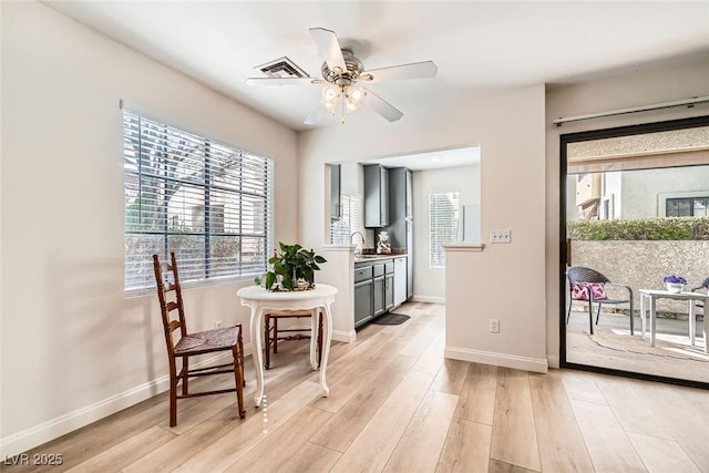 sitting room with a wealth of natural light, baseboards, light wood finished floors, and ceiling fan