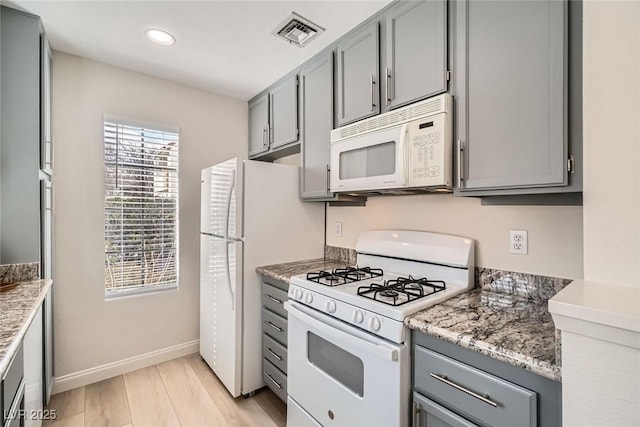 kitchen with visible vents, white appliances, and gray cabinetry