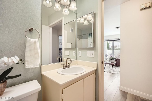 bathroom with vanity, toilet, wood finished floors, and visible vents