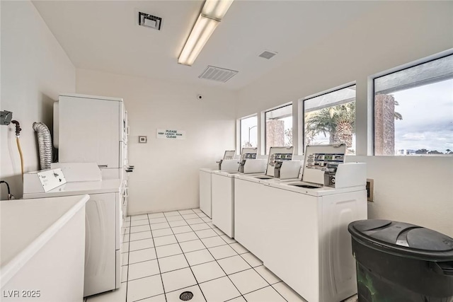 community laundry room with visible vents, washing machine and dryer, and light tile patterned flooring