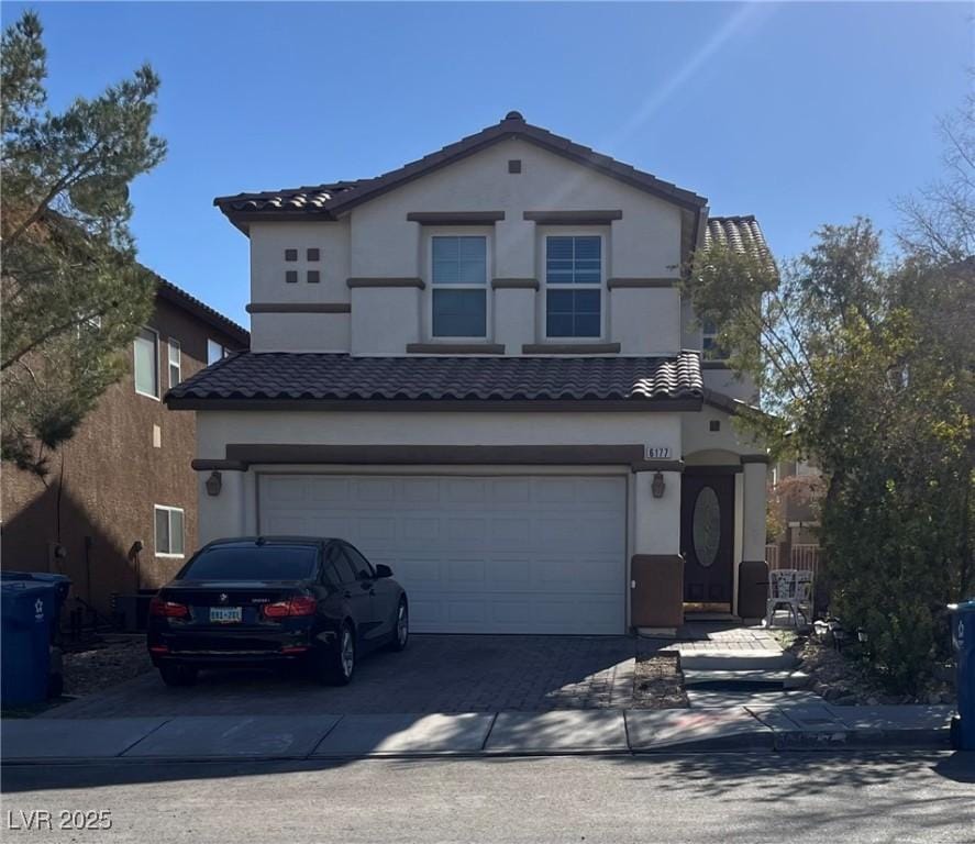 traditional-style home with a tiled roof, a garage, driveway, and stucco siding