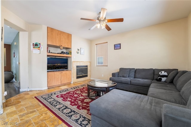 6177 W Cougar Ave, Las Vegas, NV 89139 - living area with baseboards, a tiled fireplace, a ceiling fan, and stone finish floor
