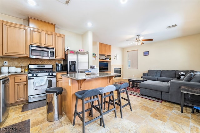6177 W Cougar Ave, Las Vegas, NV 89139 - kitchen featuring visible vents, ceiling fan, a breakfast bar area, decorative backsplash, and appliances with stainless steel finishes