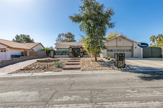 view of front of house featuring fence, concrete driveway, an attached garage, and a gate