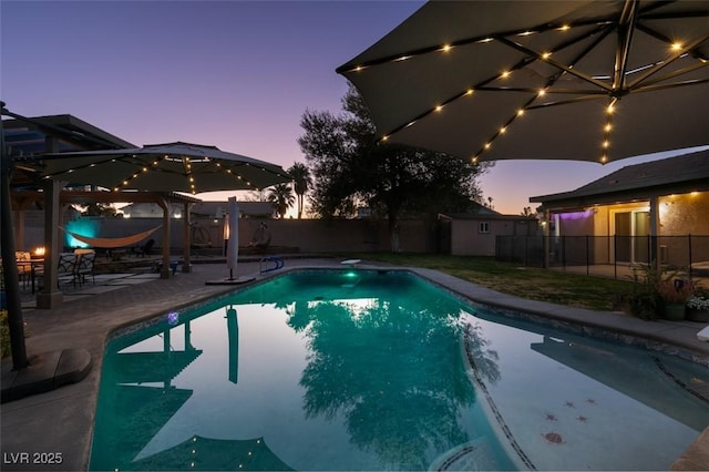 view of swimming pool featuring a patio, a fenced backyard, a fenced in pool, and an outdoor structure