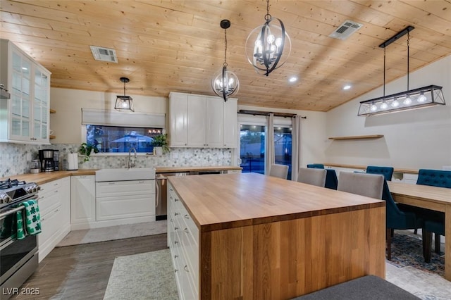 kitchen featuring visible vents, butcher block countertops, appliances with stainless steel finishes, white cabinetry, and a sink