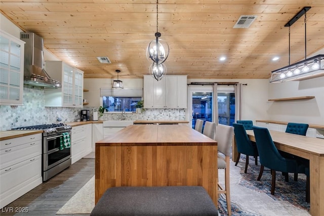 kitchen with range with two ovens, visible vents, butcher block countertops, and wall chimney exhaust hood