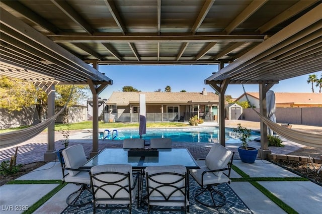 view of patio / terrace featuring a fenced in pool, a storage shed, a fenced backyard, and outdoor dining space