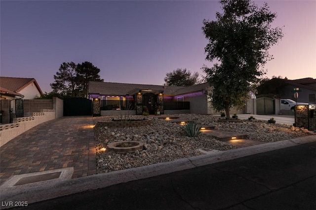 view of front of property with decorative driveway, fence, and a gate