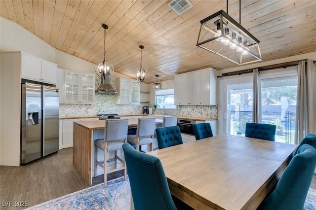 dining room with visible vents, light wood-style flooring, wooden ceiling, and lofted ceiling