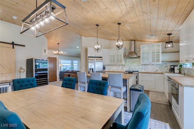 dining area featuring visible vents, wood finished floors, a barn door, an inviting chandelier, and wooden ceiling