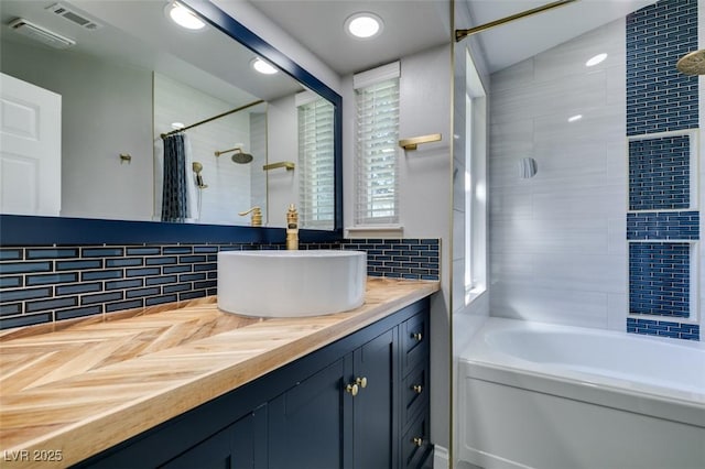 full bathroom with decorative backsplash, shower / tub combo with curtain, visible vents, and vanity