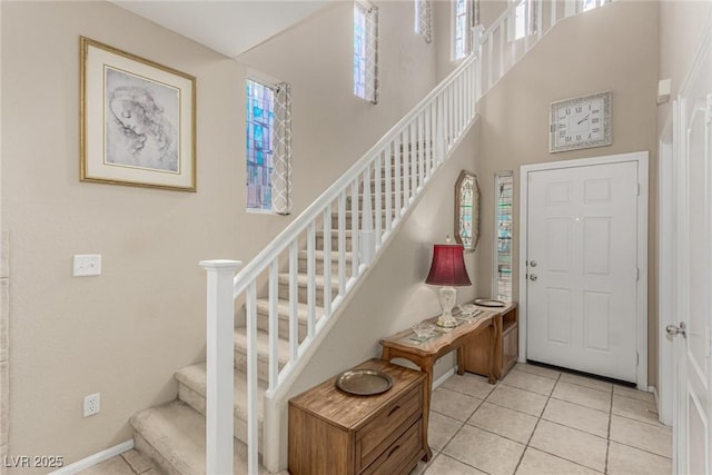 entrance foyer with stairway, a high ceiling, light tile patterned flooring, and baseboards