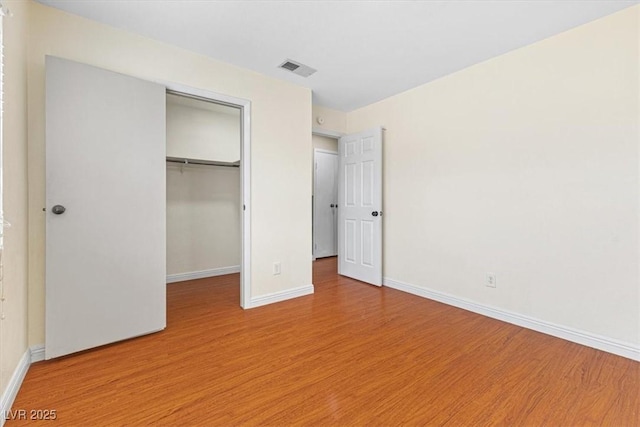 unfurnished bedroom with a closet, baseboards, light wood-style floors, and visible vents