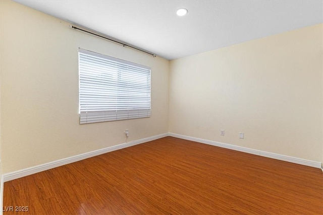 unfurnished room featuring recessed lighting, wood finished floors, and baseboards