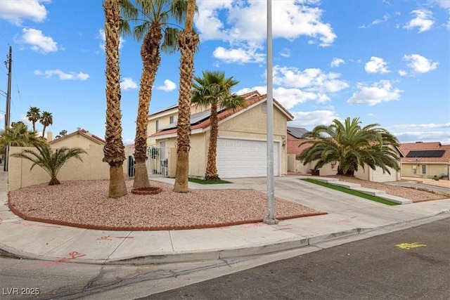 view of front facade featuring stucco siding, driveway, fence, an attached garage, and solar panels