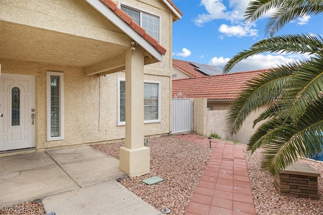 view of exterior entry featuring stucco siding and fence