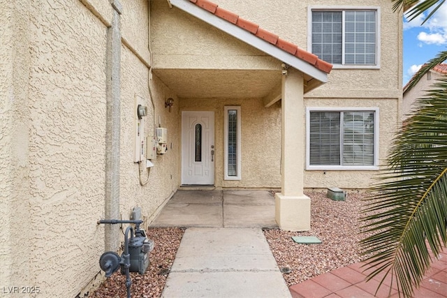 entrance to property with stucco siding and a tile roof