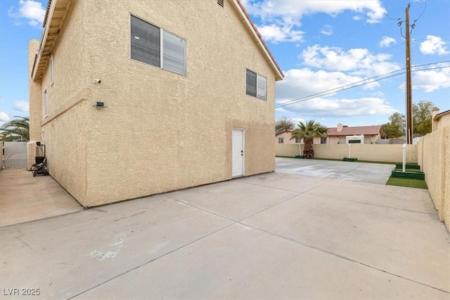 view of home's exterior with stucco siding, a fenced backyard, and a patio area