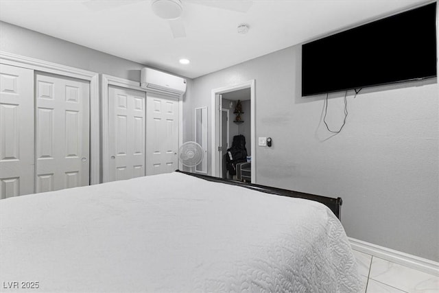 bedroom with two closets, baseboards, a wall mounted air conditioner, marble finish floor, and a ceiling fan