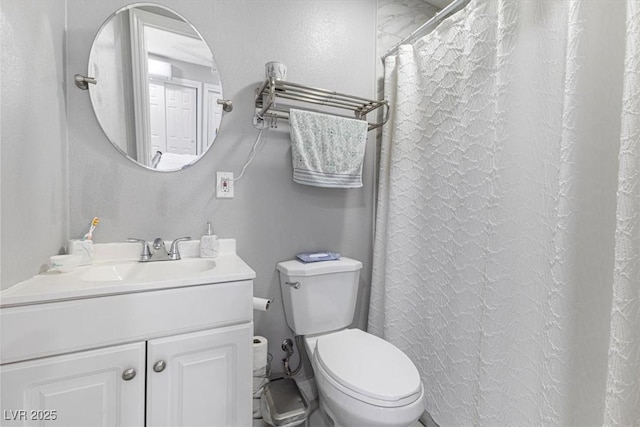 full bath featuring toilet, vanity, and a textured wall